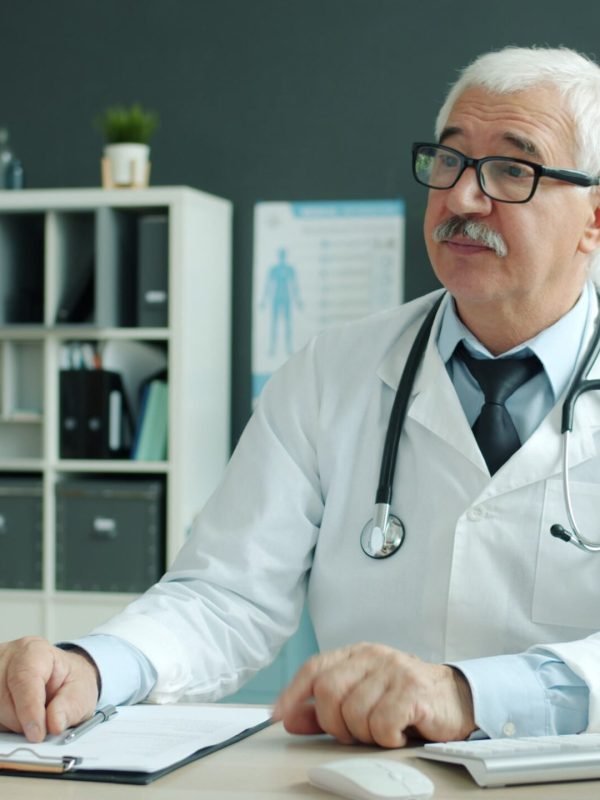 Senior doctor discussing health with patient in a modern medical office.